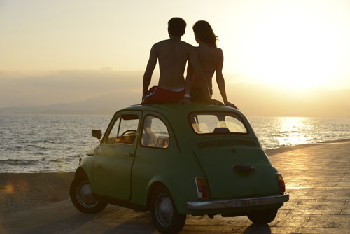 Pareja contemplando la playa arriba de un carro