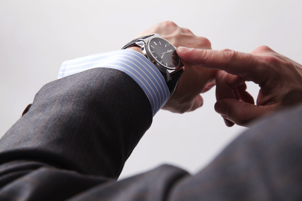 Hombre trajeado tocando su reloj con un dedo