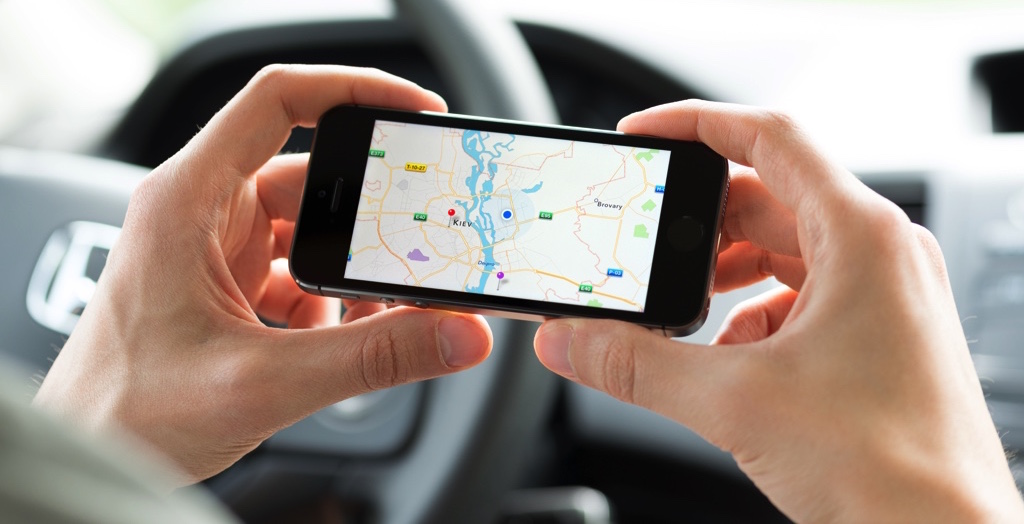 Persona agarrando su celular con las dos manos viendo un mapa de Google Maps