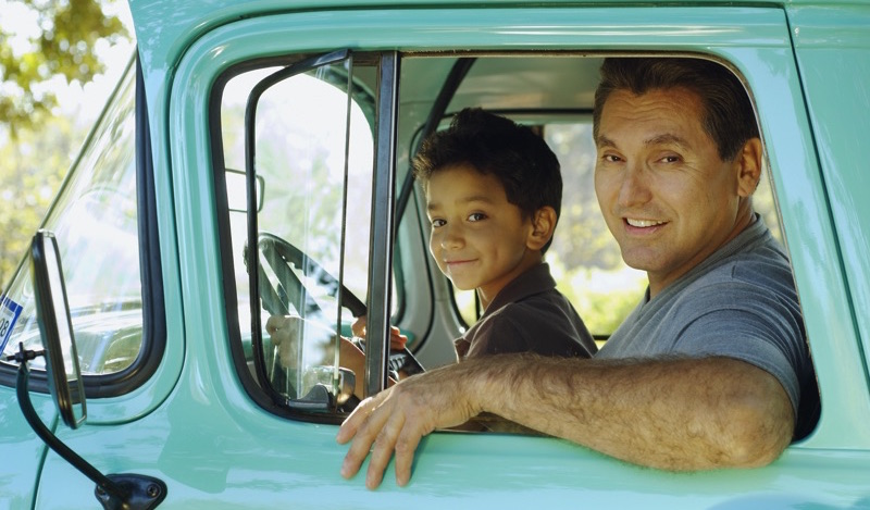 Padre e hijo sonriendo en una camioneta