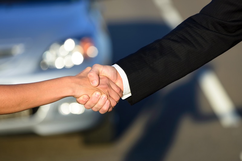 Dos personas tomándose de la mano con un fondo desenfocado de un auto