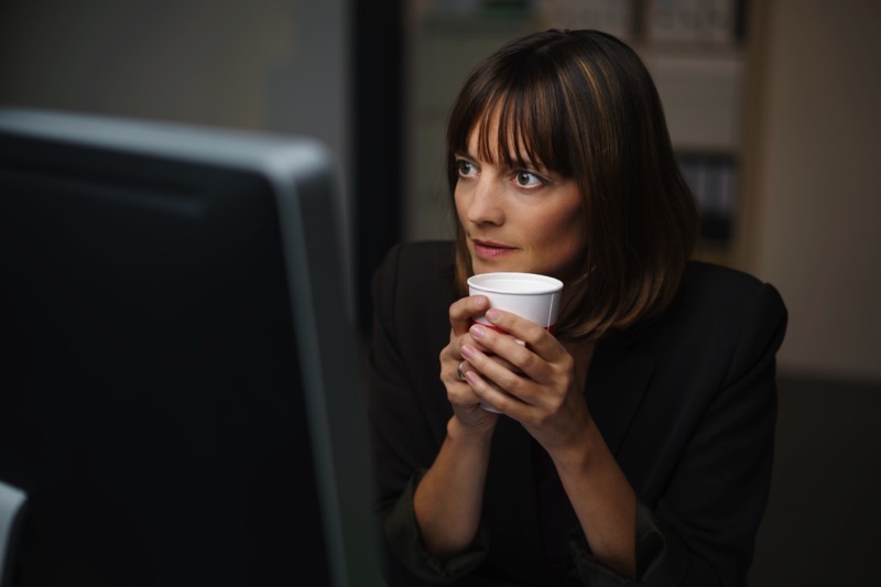 Mujer enfrente de una computador con café en mano