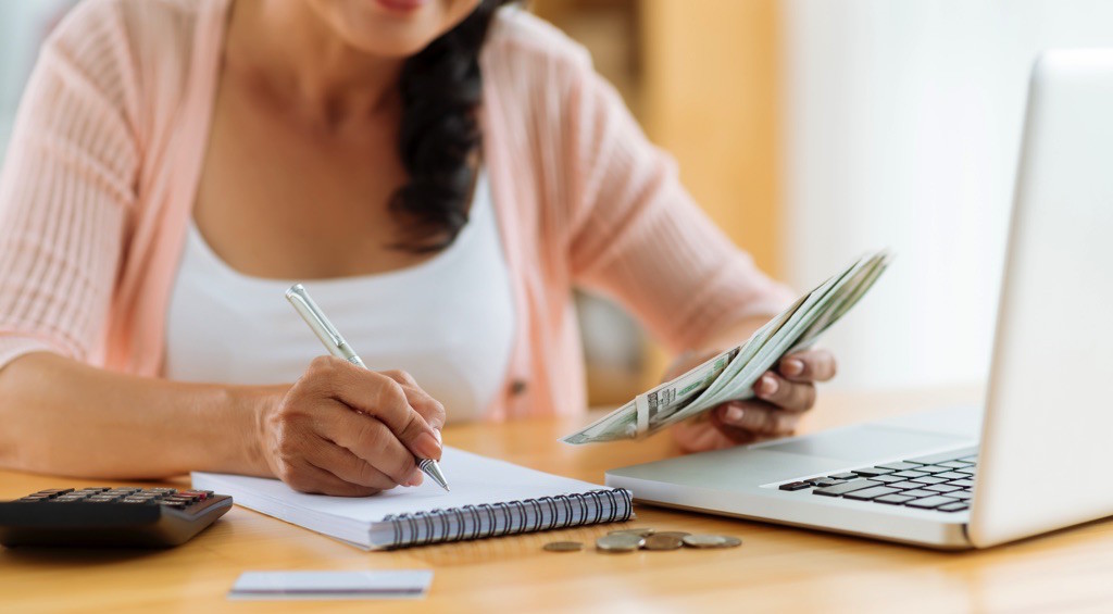 Mujer revisando sus finanzas con libreta y laptop