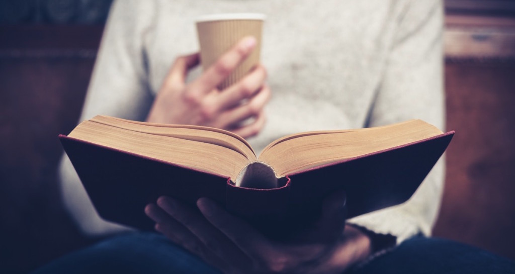 Persona con un café leyendo