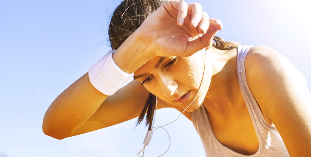 Mujer con ropa deportiva, cansada ve hacia al piso