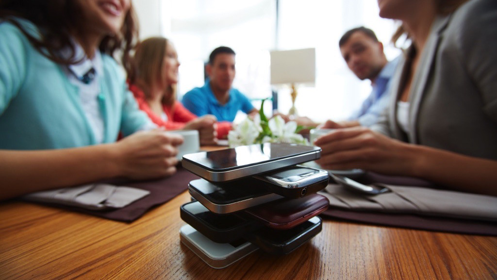 Grupo de amigos pone su celular en una esquina de la mesa para minimizar distracciones