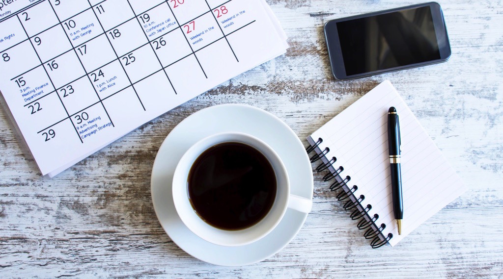 Calendario, taza de café y libreta para escribir prioridades