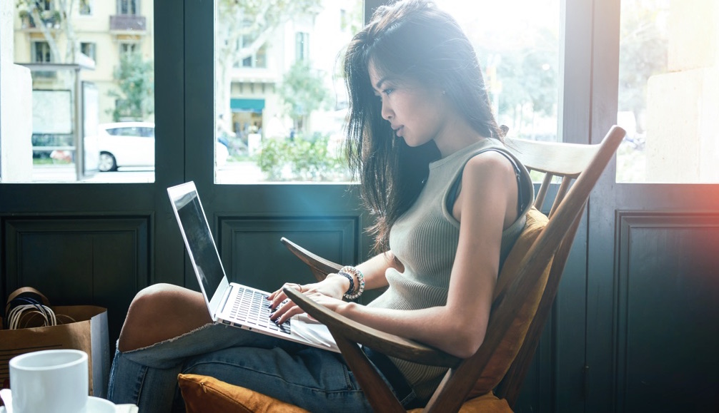 Mujer sentada escribiendo en una laptop