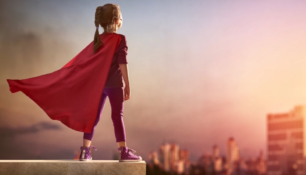 Niña superheroína en el borde de un edificio