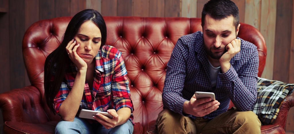 Una pareja sentada usando cada quien su celular aburridos