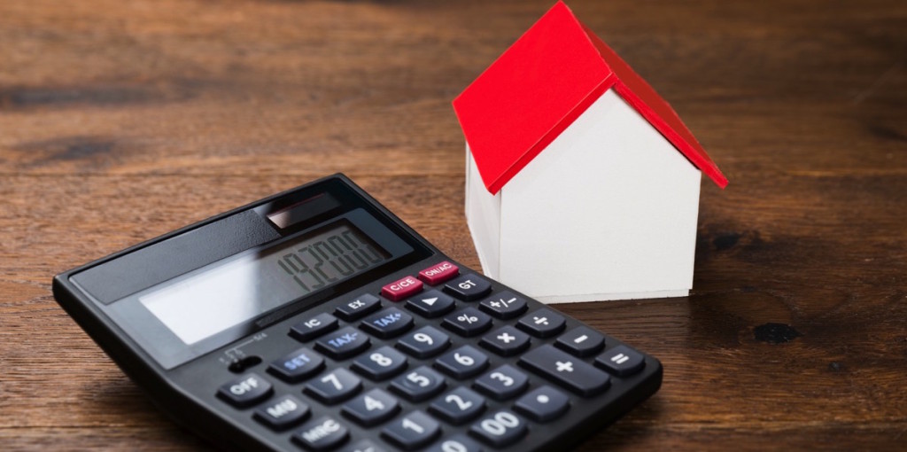 Una casa junto a una calculadora gris