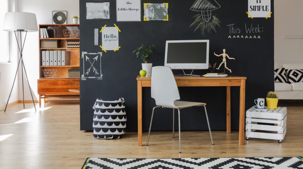 Casa con escritorio, alfombra, cuadros, lámpara y estante en acabado minimalista