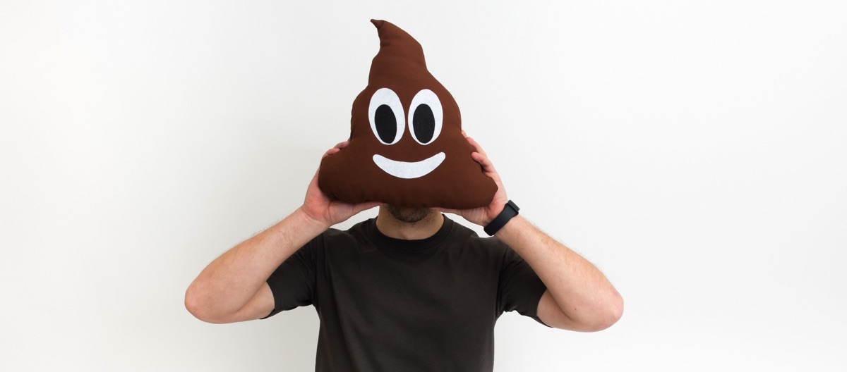 Hombre con peluche de emoji poop 