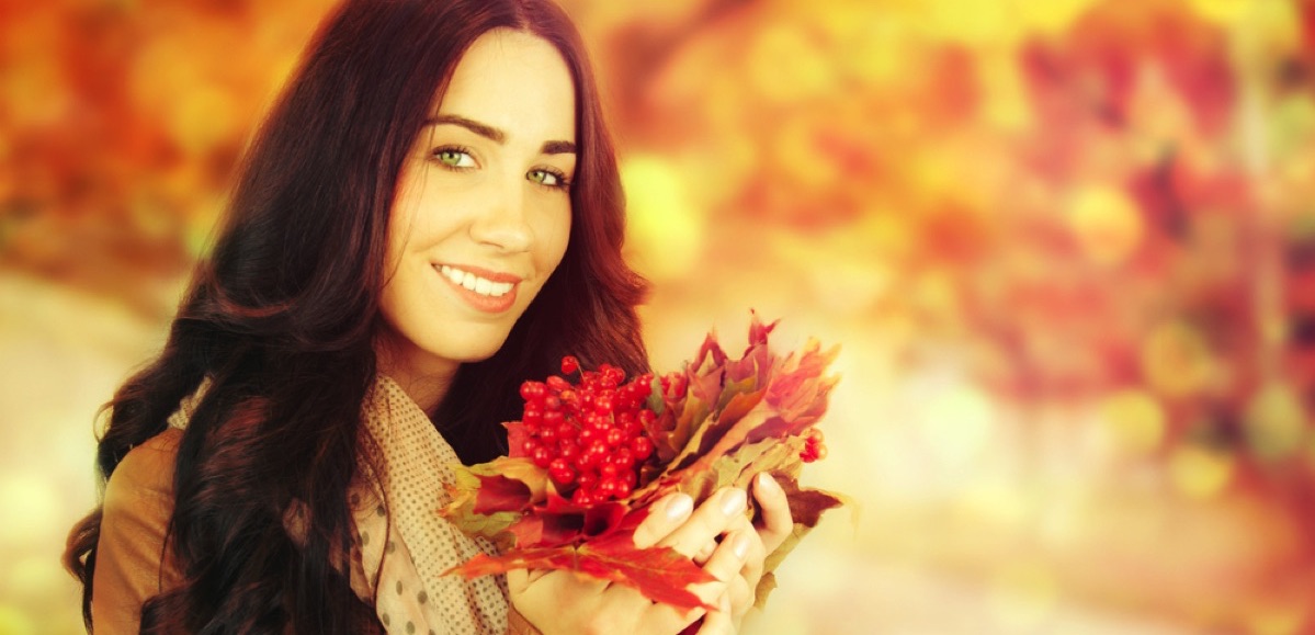 Mujer sonriendo con hojas de otoño