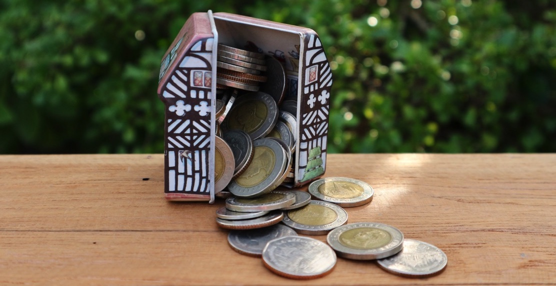 Alcancía en forma de casa abierta con muchas monedas