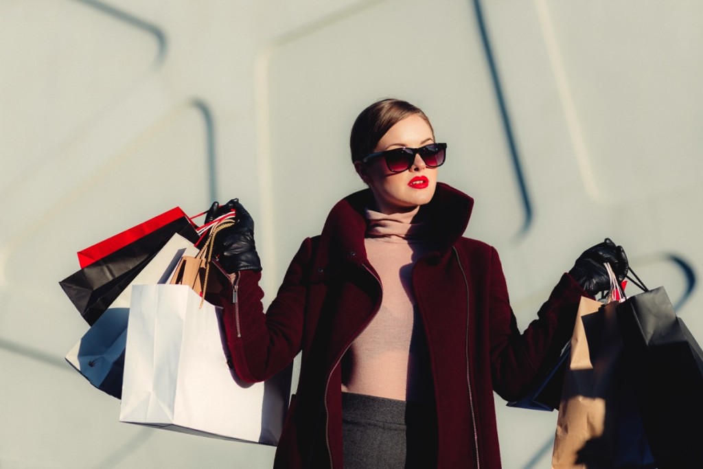 Mujer con lentes cargando muchas bolsas de compra