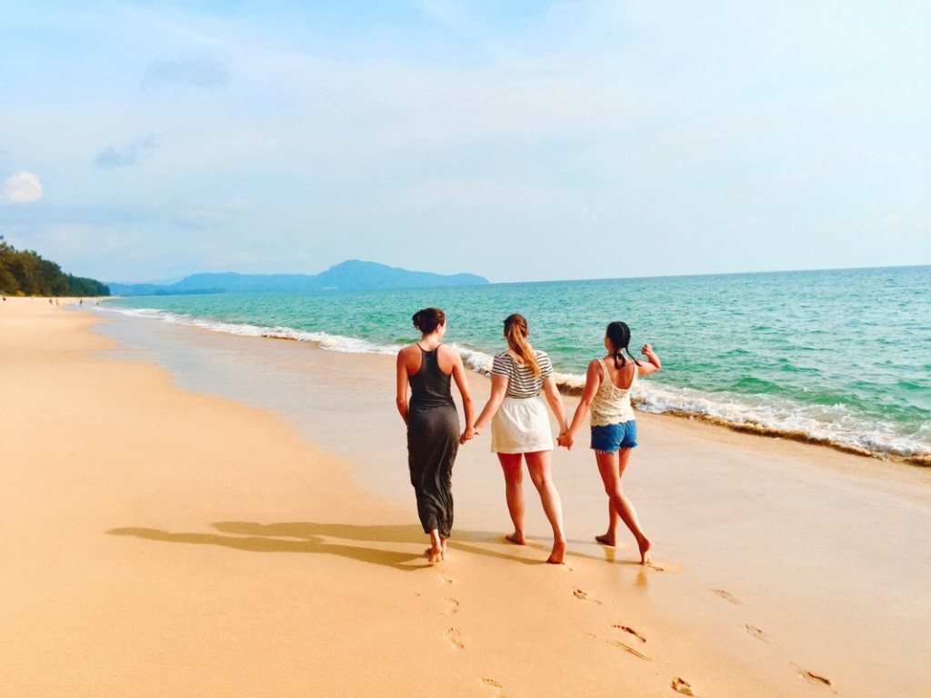 Tres amigas tomadas de la mano en una playa