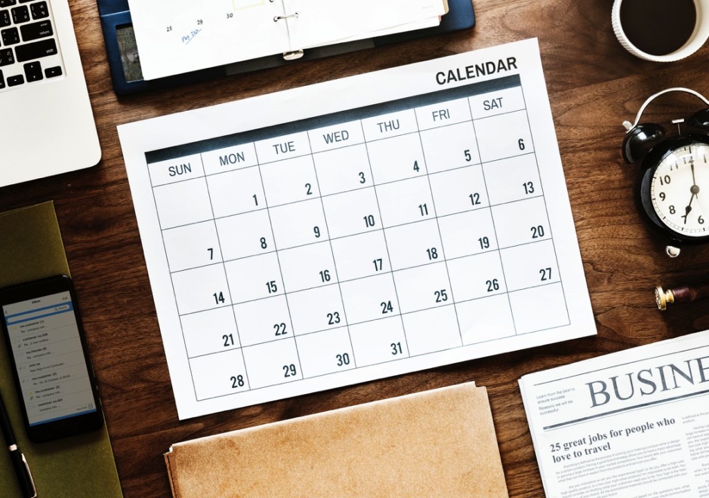 Escritorio de madera con calendario semanal, alarma y laptop